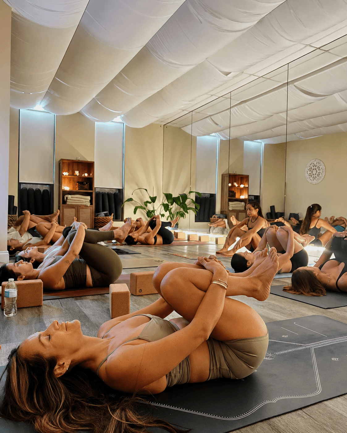 A group yoga class mid-pose in the mirrored Align Studio, mats and cork blocks on the floor